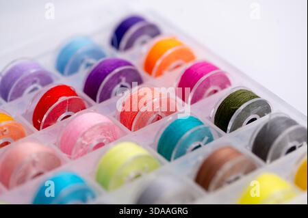 Les bobines de filetage sont disposées soigneusement dans Un conteneur avec de nombreuses couleurs. Banque D'Images