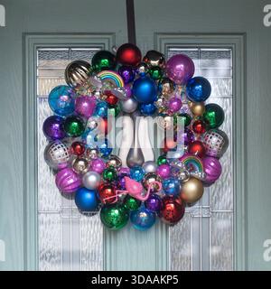 Une couronne de noël très colorée et originale faite entièrement de boules multicolores brillantes, y compris de petits arcs-en-ciel et un flamant rose, accrochée à un père Banque D'Images