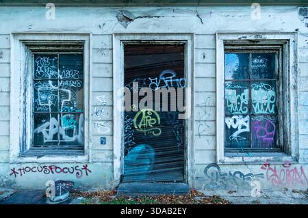 Façade de bâtiment délabrée dans le centre de Potsdam, avec plâtre altéré, portes et fenêtres arborées, et de nombreuses étiquettes graffiti. Banque D'Images