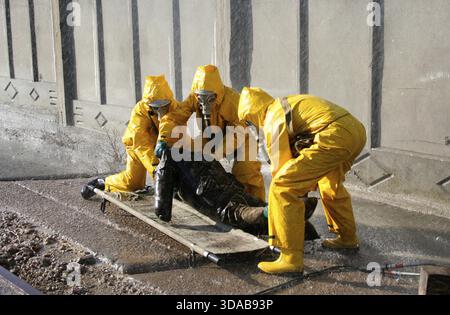 Homme dans un costume jaune de protection chimique courir sous la pluie Banque D'Images