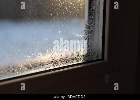 De la condensation se forme sur une fenêtre, montrant la nécessité d'une ventilation et d'une gestion de l'humidité adéquates dans une maison. Cela souligne l'importance de prévenir les moisissures et les champignons dans les espaces intérieurs. Banque D'Images