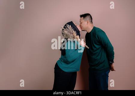 Un couple dans une pose romantique dans un studio avec un fond brun pastel Banque D'Images