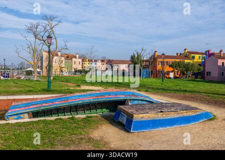 Île de Burano avec des maisons et des bateaux à rames à l'envers sur terre dans la lagune vénitienne, en Italie. Banque D'Images