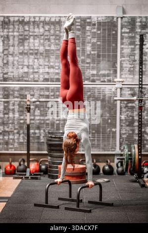 Femme équilibrant la tête en bas, démontrant la force et la concentration pendant l'entraînement calisthenics Banque D'Images