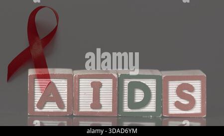Ruban rouge avec des blocs spellingÂ les aides sont debout sur une surface réfléchissante dans un design plat pour la santé Banque D'Images