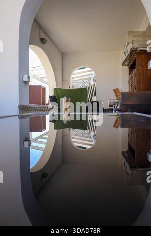 Les courbes architecturales et les éléments ménagers forment un reflet visuellement équilibré sur une surface polie, ajoutant profondeur et attrait géométrique. Banque D'Images