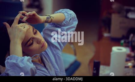 Ballerina preparing hair in dressing room before stage ritual. Banque D'Images