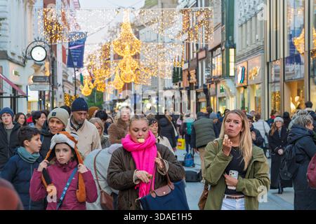 Dublin Noël shopping ruée avec les gens mangeant sur la route sous les lustres lumineux sur Grafton Street Banque D'Images