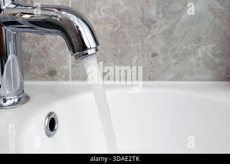 L'eau coûteuse coule d'un robinet, gros plan. Banque D'Images