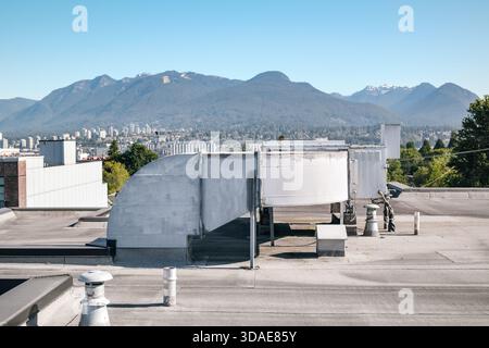 Unité HVAC sur toit plat avec ville défocalisée et montagnes. Grande unité d'air d'appoint de toit ou unité de toit emballée sur un strat résidentiel ou commercial Banque D'Images