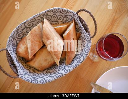 Vue de haut en bas et de près du pain baguette fraîchement tranché servi dans un panier en osier bordé d'un tissu à motifs. Le brun doré croustillant b Banque D'Images