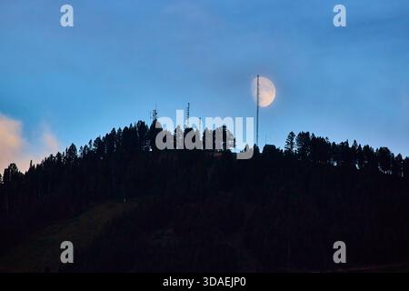 Silhouette de la tour radio avec Lune levante au-dessus de Forest Ridge à Twilight Wyoming Banque D'Images
