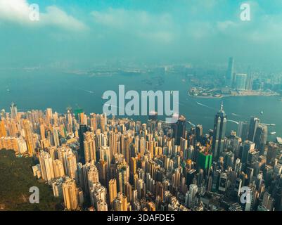 Vue aérienne de gratte-ciel perçant le ciel, avec l'emblématique port Victoria scintillant en contrebas, l'île de Hong Kong, Hong Kong. Banque D'Images