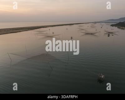 Vue aérienne de filets de pêche symétriques reflétant les eaux tranquilles sous un ciel doux, à l'aube, Hoai Nhon, Binh Dinh, Vietnam. Banque D'Images