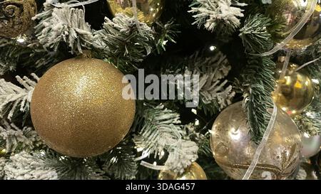 Arbre de Noël brillant de luxe avec boules dorées et métalliques, pommes de pin, feuilles et guirlande lumineuse. Motif de vacances de Noël. Design tendance et créatif. Banque D'Images