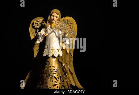 Figurine d'ange d'or dramatique jouant du violon sur fond noir Banque D'Images