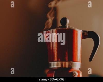 L'essence d'une matinée chaleureuse avec ce pot de moka rouge vif et fumant. Parfait pour illustrer la préparation du café maison, authentique espresso cultu italien Banque D'Images