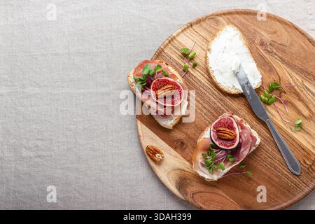 Tranches de pain blanc avec fromage à la crème jeune, prosciutto, figues fraîchement tranchées et pousses de radis. Un délicieux apéritif pour le vin sur la table avec un Banque D'Images