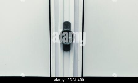 Gros plan du cadran en plastique gris moderne ou du mécanisme de verrouillage sur la porte de salle de bains en PVC blanc ou le cadre de fenêtre Banque D'Images