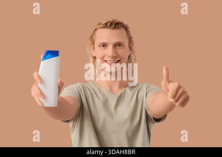 Jeune homme blond avec shampooing montrant pouce vers le haut sur fond beige Banque D'Images