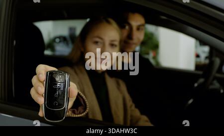 Heureux couple assis dans la voiture et célébrant un nouvel achat Banque D'Images
