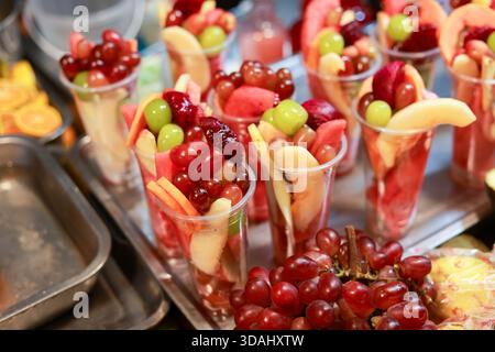 Délicieuses tasses de salade de fruits frais et colorés prêtes à manger. collation saine du marché de la nourriture de rue. Ce mélange appétissant et rafraîchissant comprend du raisin Banque D'Images