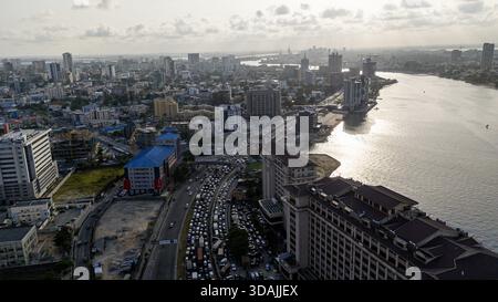 Vue aérienne du paysage urbain animé où les bâtiments brillants rencontrent les eaux ensoleillées de la lagune, Lagos, Lagos, Nigeria. Banque D'Images