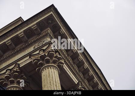 Vue rapprochée de la colonnade corinthienne classique présentant des chapiteaux détaillés et de l'entablature sous une lumière du jour douce et diffuse avec un bac de ciel neutre Banque D'Images