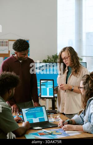 Jeune femme caucasienne présentant la stratégie de marketing numérique à l'équipe diverse Banque D'Images