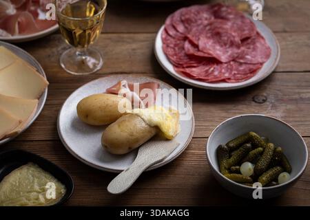 Raclette avec pommes de terre au four, salami, fromage et cornichons marinés Banque D'Images