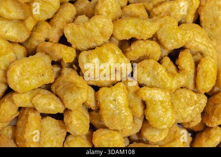 Une vue rapprochée et de haut en bas d'un grand tas de nuggets de poulet panés dorés, mettant en valeur leur surface texturée et leur aspect invitant Banque D'Images