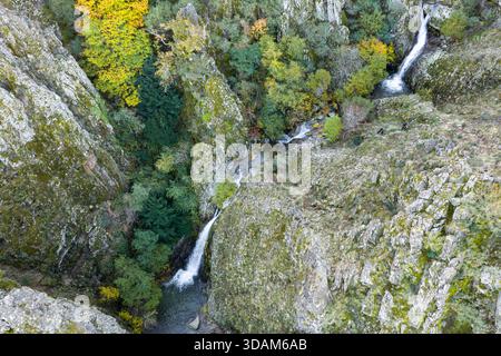 Vue aérienne des cascades plonger dans les falaises accidentées, embrassées par le feuillage automnal à Pozo do Inferno, Manteigas, Portugal. Banque D'Images