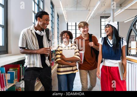 Groupe multiethnique de jeunes étudiants se réunissant à la bibliothèque - groupe d'étudiants multiethniques heureux collaborant et profitant du temps tout en marchant à travers Banque D'Images