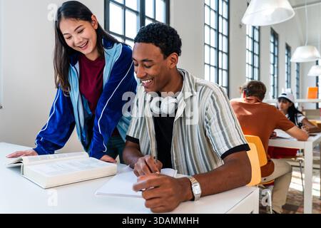 Groupe multiethnique de jeunes étudiants se réunissant à la bibliothèque - jeunes étudiants multiethniques collaborant à une mission dans une bibliothèque moderne lumineuse, lea Banque D'Images