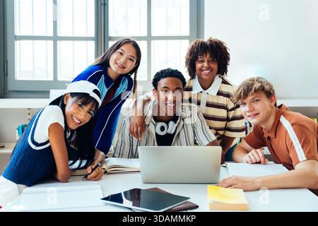 Groupe multiethnique de jeunes étudiants se réunissant à la bibliothèque - divers adolescents collaborant sur le projet à la bibliothèque, assis autour de la table avec l'ordinateur portable A. Banque D'Images