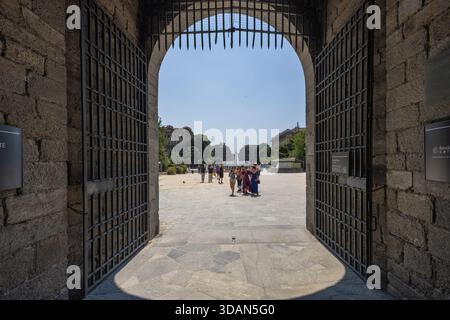 MILAN, ITALIE, 06.19.2025 :Une grande arche en pierre encadre une cour ensoleillée menant à une place animée de la ville. Contraste entre les passages ombragés et A. Banque D'Images