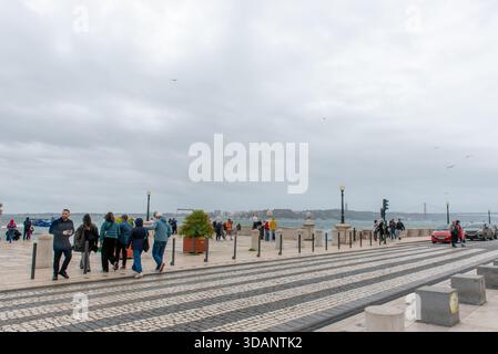 Marchant les gens, les touristes sur les rives du Tage, près de Praca do Comercio, Lisbonne, Portugal. Temps venteux et pluvieux. Banque D'Images