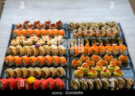Une gamme vibrante de nombreux types différents de sushis gastronomiques et de rouleaux de maki, présentant diverses saveurs et une présentation artistique, est disposée sur le pl noir Banque D'Images