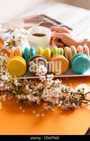 Beaucoup de macarons classiques sur des plats blancs, sur un fond orange à la lumière naturelle Banque D'Images