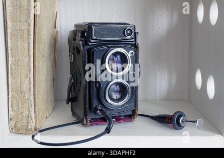 Appareil photo TLR vintage avec déclencheur externe sur la bibliothèque blanche Banque D'Images