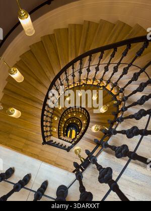 Escalier en colimaçon de dessus avec balustrade ornée et lampes chaudes crée une ambiance historique élégante. Banque D'Images