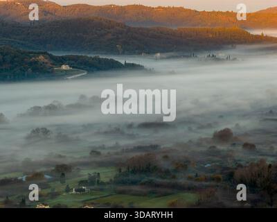 Lumière dorée spectaculaire du lever du soleil frappant les sommets des montagnes au-dessus d'une mer d'épais brouillard blanc. Route sinueuse sur une colline surplombant une vallée brumeuse. Contre-courant élevé Banque D'Images
