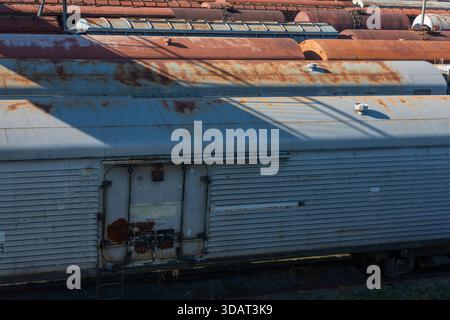 Wagons de train de marchandises rouillés debout à la lumière du soleil, avec des surfaces métalliques texturées et des détails industriels, idéal pour le transport et la décomposition urbaine Banque D'Images