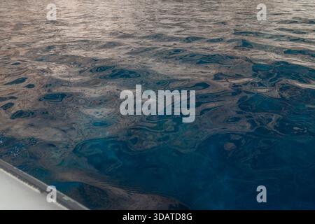 Vue rapprochée de l'eau de mer bleu profond avec des reflets doux du soleil. Les ondulations douces créent une texture marine abstraite et apaisante adaptée aux arrière-plans Banque D'Images