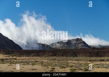 Vue sur le terrain volcanique accidenté rencontre le ciel, nuages tourbillonnent autour des sommets, peignant une scène dramatique de la beauté brute de la nature, Tenerife, Islan Canaries Banque D'Images