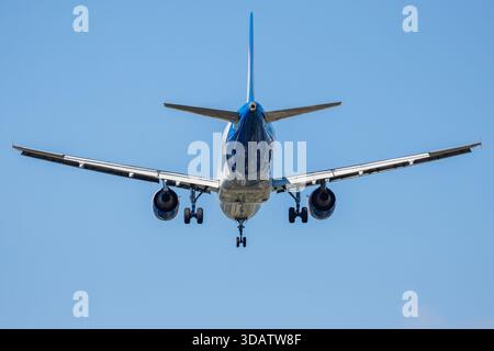 Avion de passagers atterrissant avec train d'atterrissage, vue rapprochée dans le ciel bleu Banque D'Images