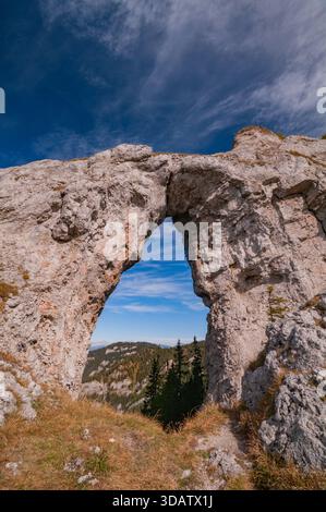 Vue sur une voûte rocheuse majestueuse encadrant les montagnes lointaines et brumeuses sous un ciel bleu vibrant, une fenêtre naturelle sur le paysage serein, Ohniste, Zilina R. Banque D'Images
