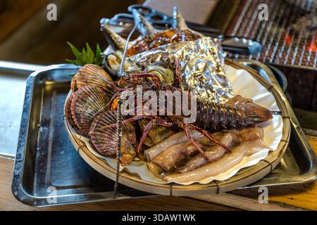 Homard Ise, calmar, coquilles Saint-Jacques, coquillage turbin et maquereau japonais sont vus de dessus sur le plateau de fruits de mer lors de l'expérience Ama Hut et du déjeuner au Satoumian Ama Hut, Shima, préfecture de Mie, Japon. Pendant l'expérience Ama Hut, les plongeurs Ama font griller des fruits de mer fraîchement pêchés pour les invités dans une réplique d'une hutte ama. Banque D'Images