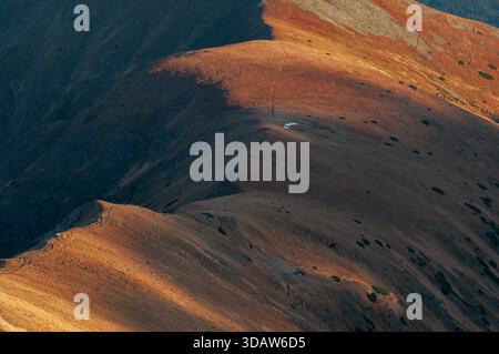 Vue aérienne des crêtes dorées automnales projetant de longues ombres, révélant une structure solitaire perchée au sommet d'un pic dans les Tatras occidentales, Zilinsky kraj, S. Banque D'Images