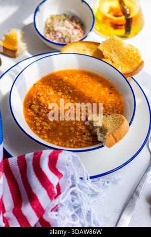 Un bol copieux de faux, soupe traditionnelle grecque aux lentilles, servi avec du pain grillé croustillant et un accompagnement d'assaisonnement. C'est un Medi réconfortant et nutritif Banque D'Images